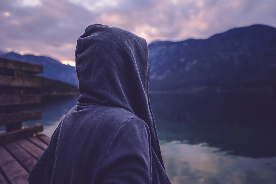 Man outside in hood feeling sad.